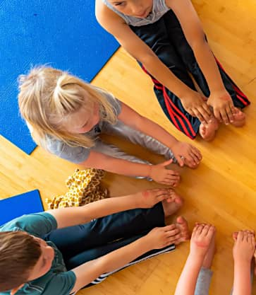 IYK® Kids Yoga Class on a wooden floor.