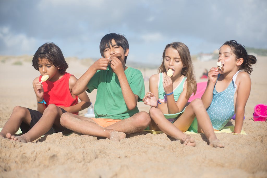 4 kids on the breach eating an ice cream bar