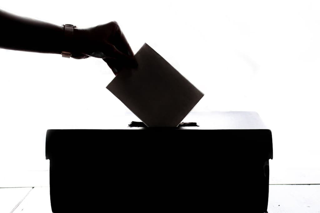 Silhouette casting a ballot in a voting box