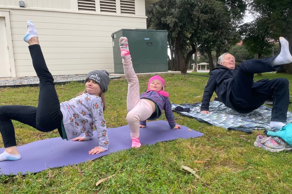 Grandfather doing yoga with his granddaughters
