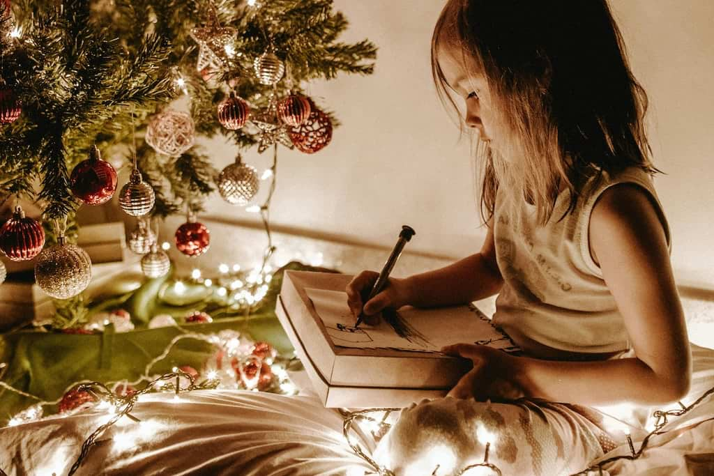 A girl writing under a Christmas tree