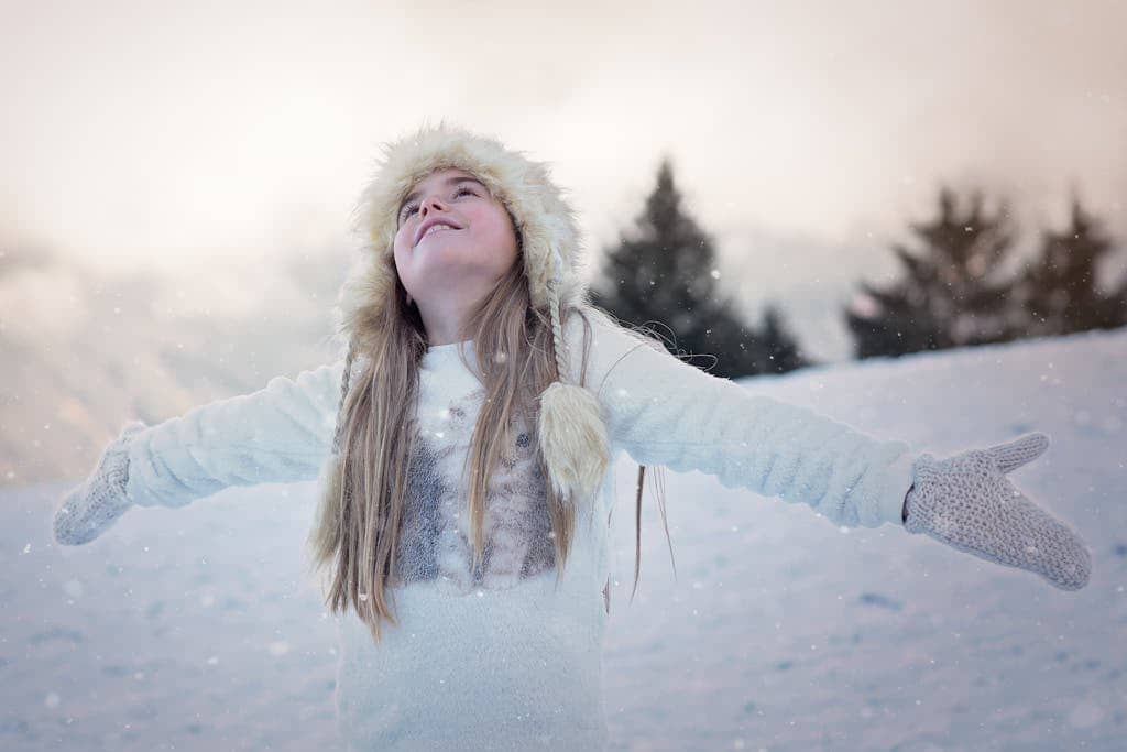 A girl looking up with arms out in the snow