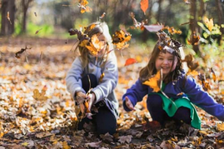 Two girls throwing fall leaves in the air