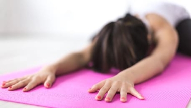 In a IYK® yoga session, a mom relaxing in a child pose.